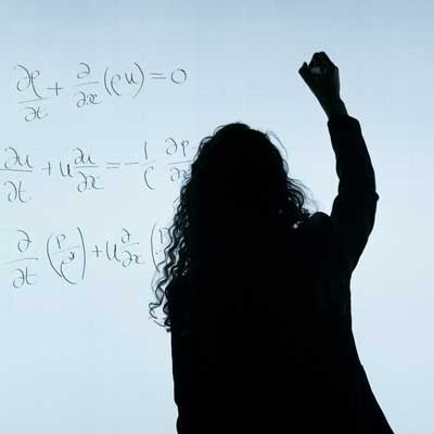 a teacher writing math problems on a whiteboard