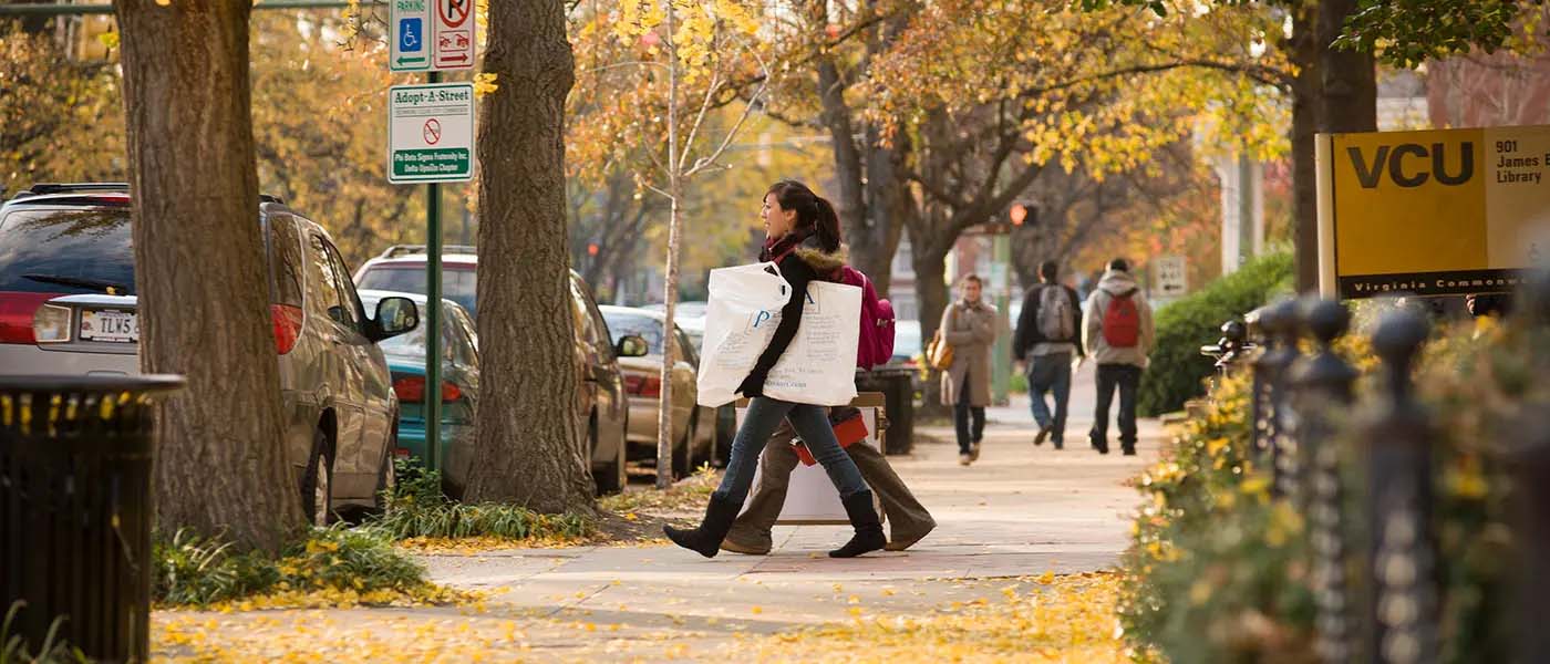 v.c.u. students walking on campus in the fall carrying posters
