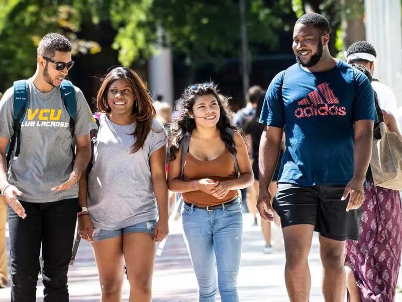 four v.c.u. students walking and laughing on a sunny day