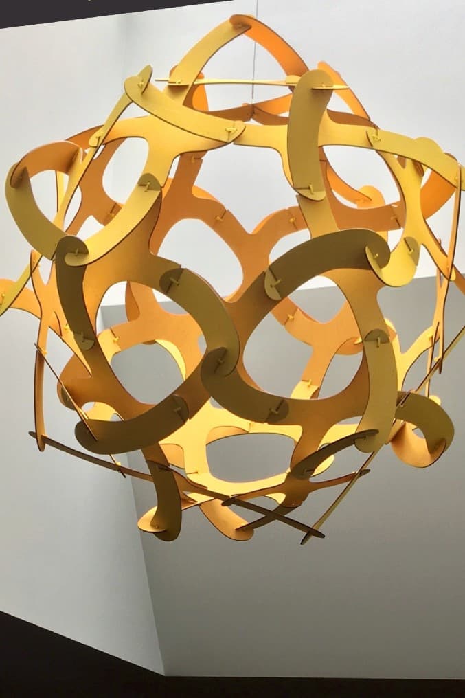 Geometric sculpture made of light wood hanging in skylight