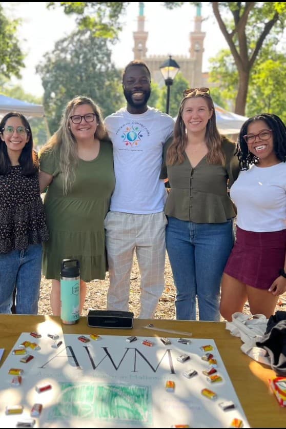 5 math graduate students in Monroe Park, sign on table reads 