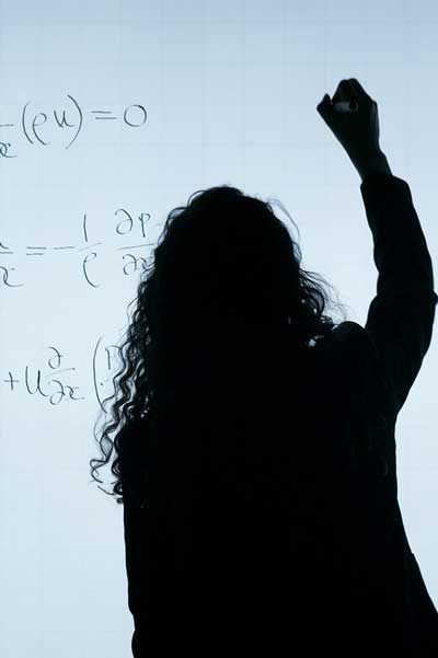 a math teacher writing math problems on a whiteboard